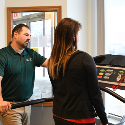 Therapist guides patient using physical therapy equipment